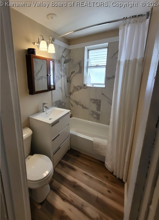 full bathroom featuring shower / tub combo with curtain, vanity, wood-type flooring, and toilet