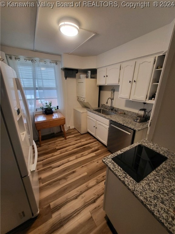 kitchen with stainless steel dishwasher, wood-type flooring, white fridge with ice dispenser, white cabinets, and sink