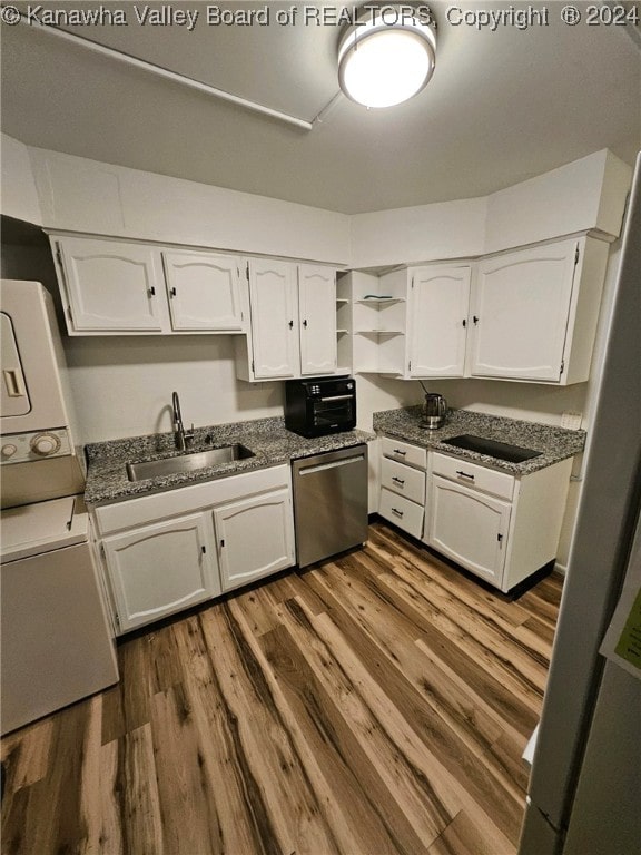 kitchen featuring white cabinets, hardwood / wood-style floors, sink, stacked washer / drying machine, and dishwasher