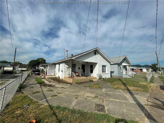 back of property featuring a yard and covered porch