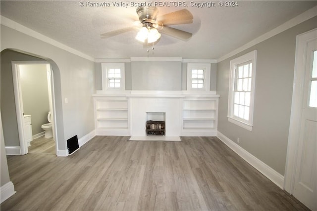 unfurnished living room featuring ceiling fan, ornamental molding, wood-type flooring, and a textured ceiling