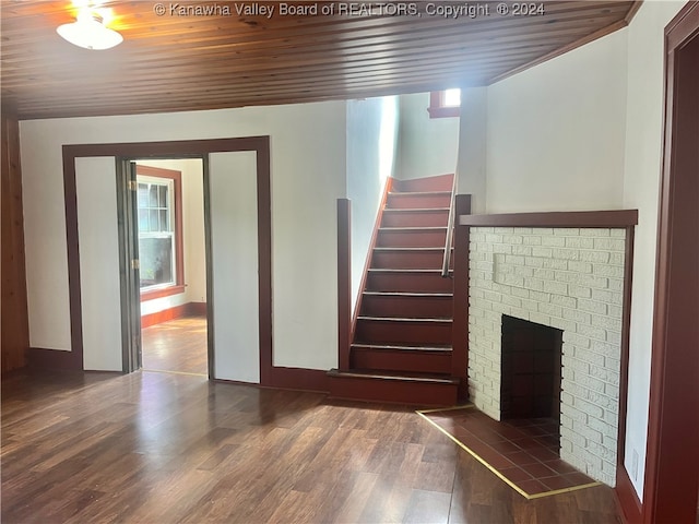 staircase featuring wooden ceiling, hardwood / wood-style floors, and a brick fireplace