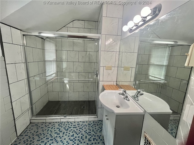 bathroom featuring a shower with shower door, vanity, tile walls, and tile patterned flooring