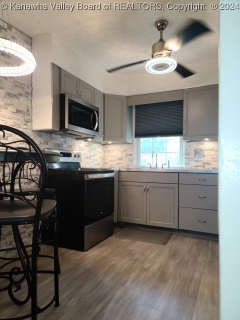 kitchen featuring backsplash, electric range oven, ceiling fan, and light hardwood / wood-style floors