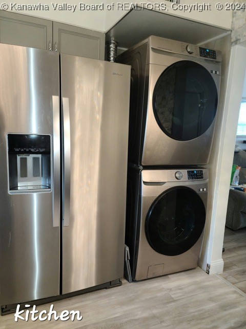 washroom with stacked washer and clothes dryer and light hardwood / wood-style floors