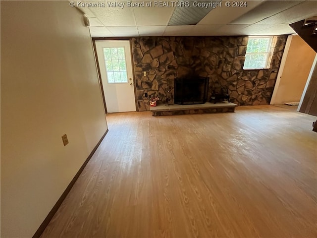 unfurnished living room with a drop ceiling, hardwood / wood-style flooring, and a fireplace