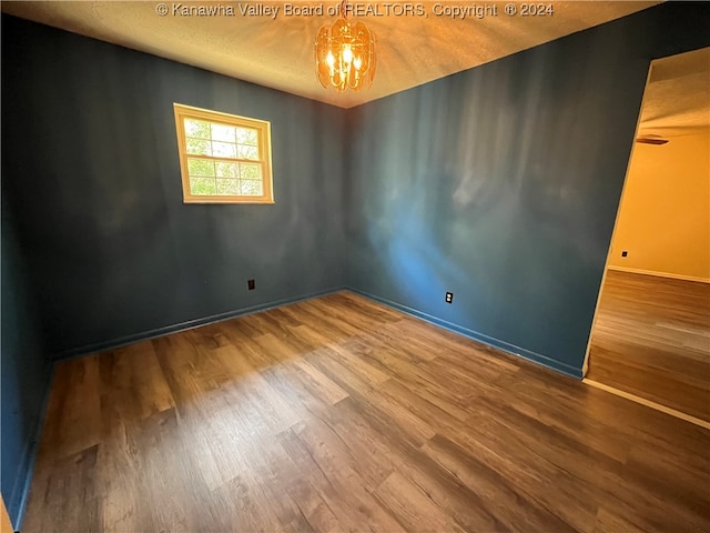 empty room featuring hardwood / wood-style floors and a chandelier