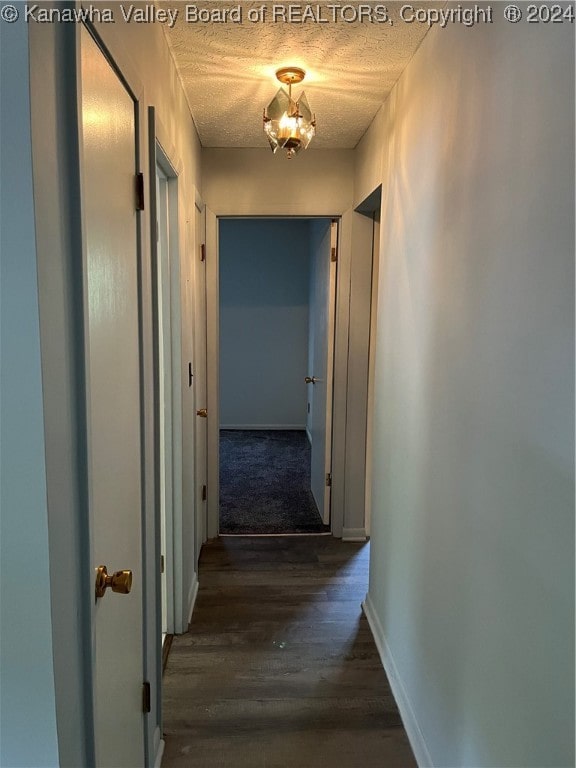 corridor with hardwood / wood-style flooring, a textured ceiling, and a chandelier