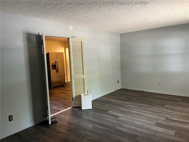 unfurnished bedroom featuring dark hardwood / wood-style flooring, a textured ceiling, and stainless steel fridge