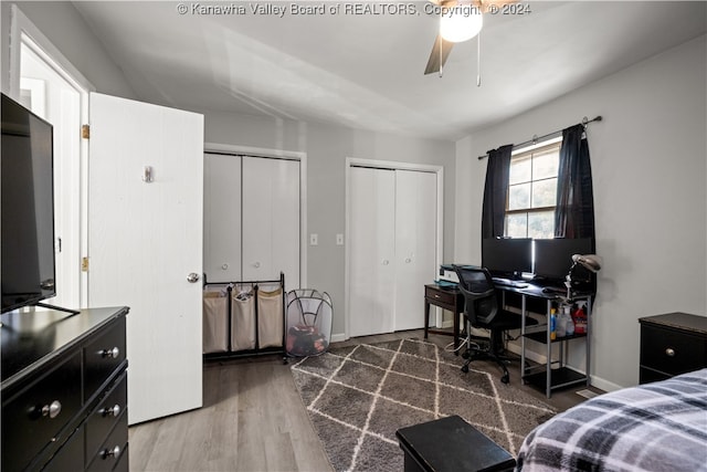 bedroom with ceiling fan, dark hardwood / wood-style floors, and multiple closets