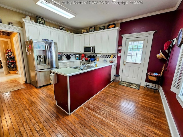 kitchen with light wood-type flooring, white cabinetry, appliances with stainless steel finishes, and tasteful backsplash