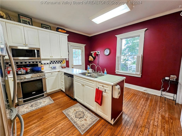 kitchen with light wood-type flooring, kitchen peninsula, appliances with stainless steel finishes, and a healthy amount of sunlight