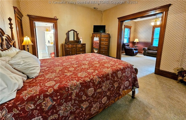 bedroom featuring connected bathroom and light colored carpet