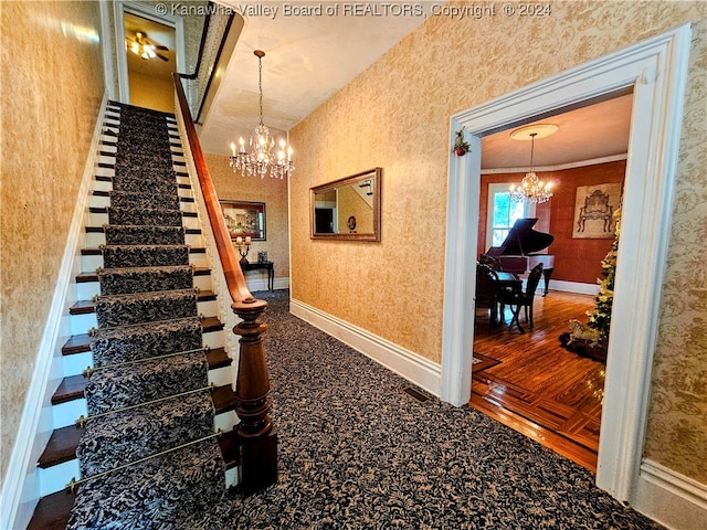 staircase featuring carpet floors, crown molding, and a notable chandelier