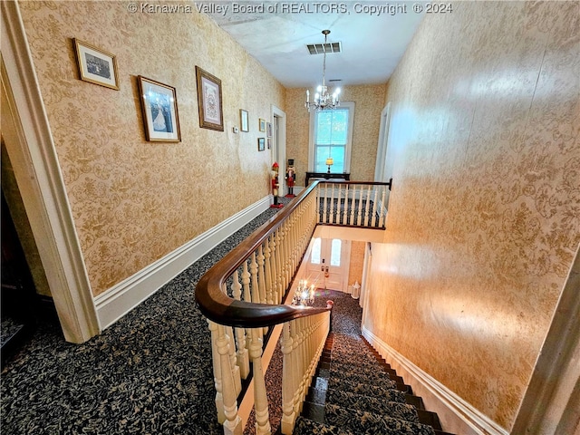 staircase with a notable chandelier and carpet floors