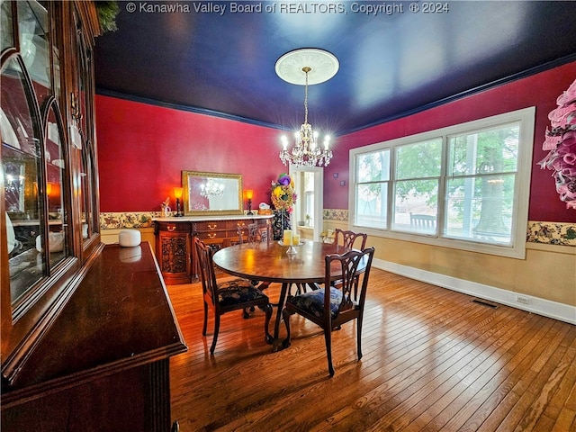 dining area featuring wood-type flooring, ornamental molding, and a chandelier