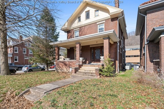 view of front of house with central air condition unit, a front yard, and covered porch