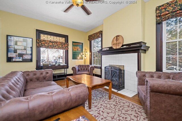 living room featuring ceiling fan, hardwood / wood-style flooring, and a fireplace