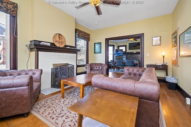 living room featuring hardwood / wood-style floors, ceiling fan, and a fireplace