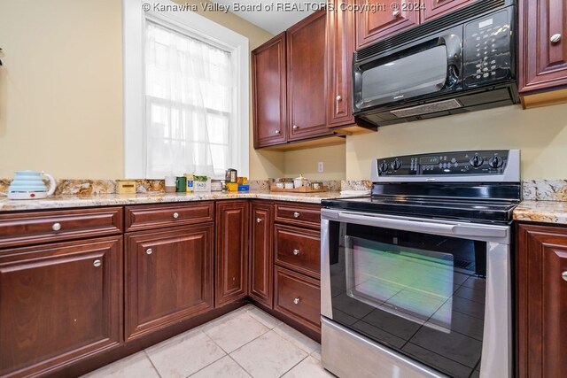 kitchen with light tile patterned floors, light stone countertops, and stainless steel range with electric stovetop