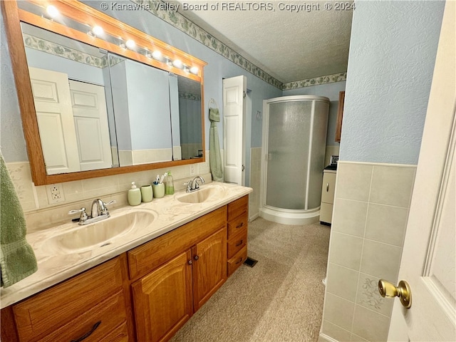 bathroom featuring decorative backsplash, a textured ceiling, a shower with door, and vanity