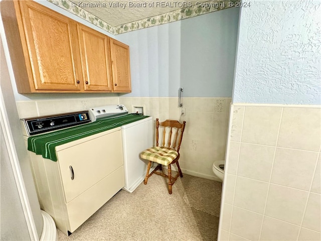 clothes washing area featuring light carpet, cabinets, and separate washer and dryer