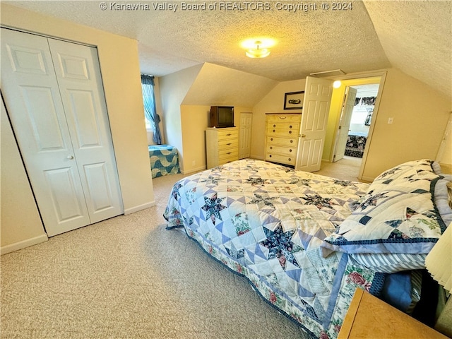 carpeted bedroom with a closet, a textured ceiling, and lofted ceiling