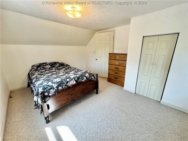 carpeted bedroom featuring a closet, a textured ceiling, and lofted ceiling