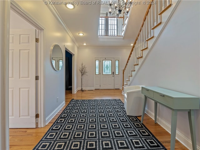 entryway with crown molding, a chandelier, and hardwood / wood-style flooring