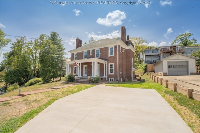 view of front of home featuring a garage, a front lawn, an outdoor structure, and a porch