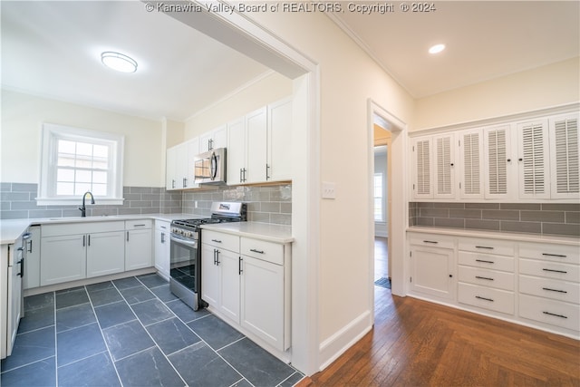 kitchen featuring decorative backsplash, dark wood-type flooring, white cabinets, sink, and range with gas stovetop