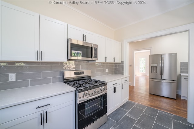 kitchen with appliances with stainless steel finishes, dark wood-type flooring, white cabinetry, and backsplash