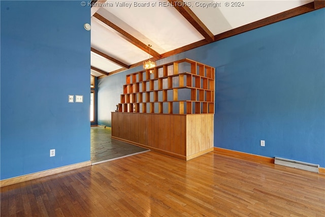 unfurnished living room with lofted ceiling with beams, wood-type flooring, and a baseboard radiator