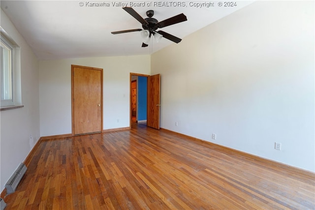 unfurnished bedroom with hardwood / wood-style flooring, a baseboard heating unit, lofted ceiling, and ceiling fan