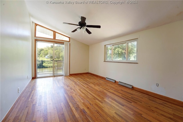 empty room featuring hardwood / wood-style floors, a wealth of natural light, vaulted ceiling, and ceiling fan