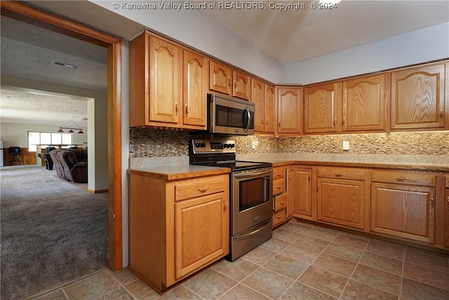 kitchen with appliances with stainless steel finishes, a textured ceiling, light carpet, and tasteful backsplash