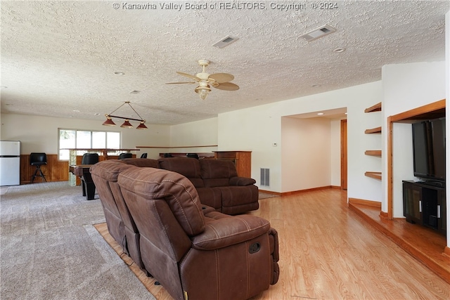 living room featuring a textured ceiling, ceiling fan, and light wood-type flooring