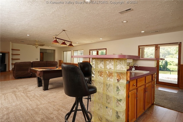 kitchen with sink, pool table, light hardwood / wood-style flooring, and a textured ceiling