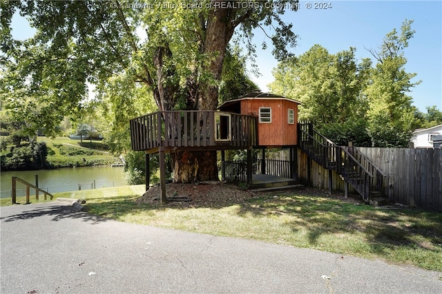 view of front of home with a deck with water view and a front lawn