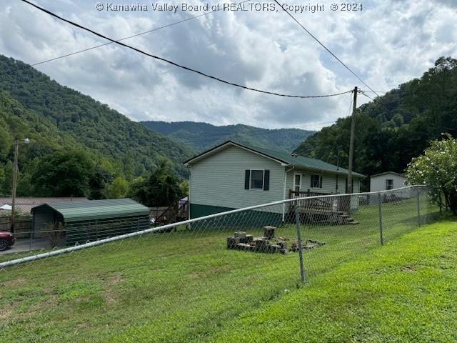 view of property exterior with a mountain view, a lawn, and fence