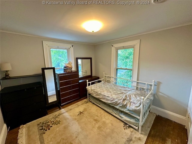 bedroom with multiple windows, hardwood / wood-style flooring, and crown molding