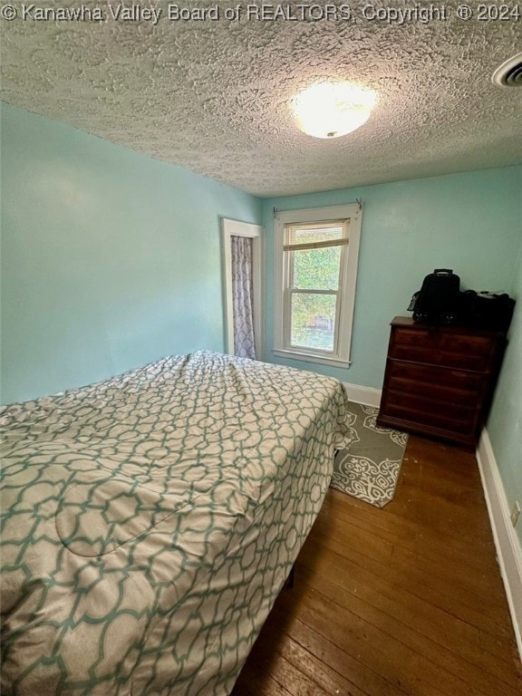 bedroom with a textured ceiling and wood-type flooring