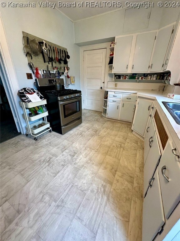 kitchen with white cabinetry, gas range, and sink