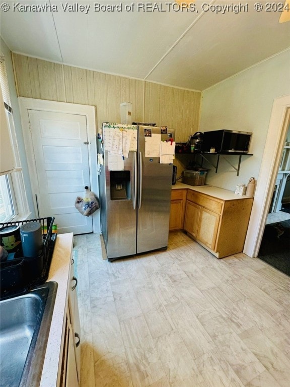 kitchen featuring wood walls, sink, and stainless steel refrigerator with ice dispenser