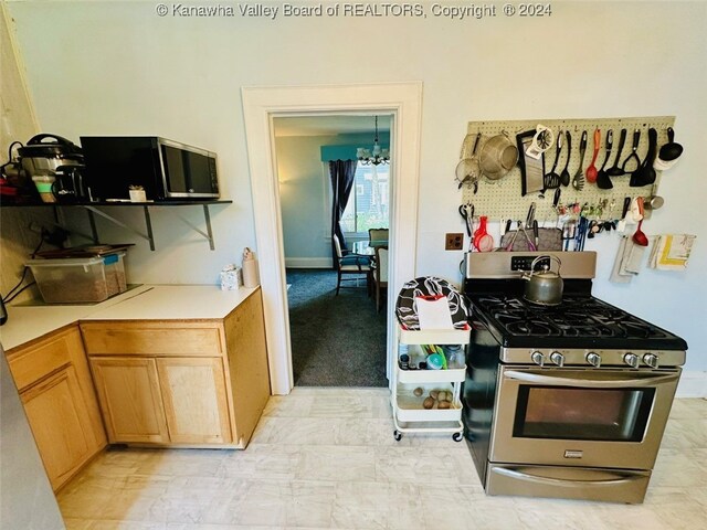 kitchen with an inviting chandelier and stainless steel gas range oven