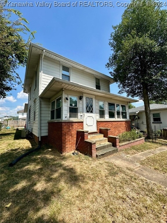 rear view of house featuring cooling unit and a lawn