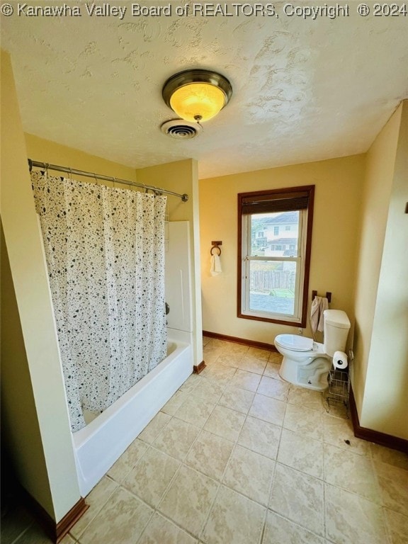 bathroom with tile patterned floors, a shower with shower curtain, toilet, and a textured ceiling