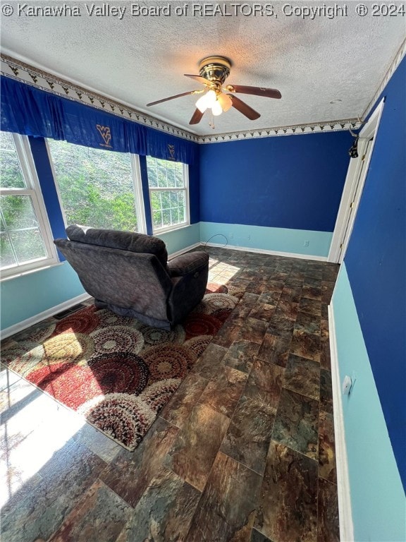 living area featuring ceiling fan, a textured ceiling, and a healthy amount of sunlight