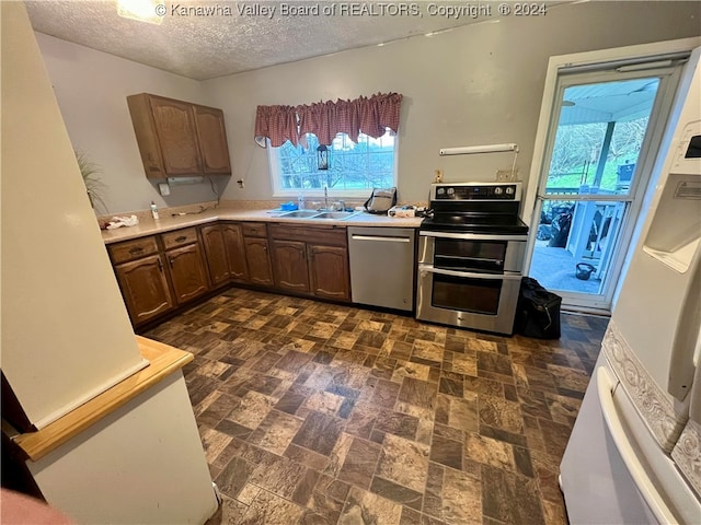 kitchen with appliances with stainless steel finishes, plenty of natural light, a textured ceiling, and sink