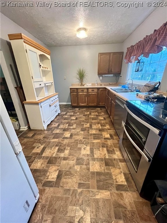 kitchen featuring a textured ceiling, stainless steel appliances, and sink